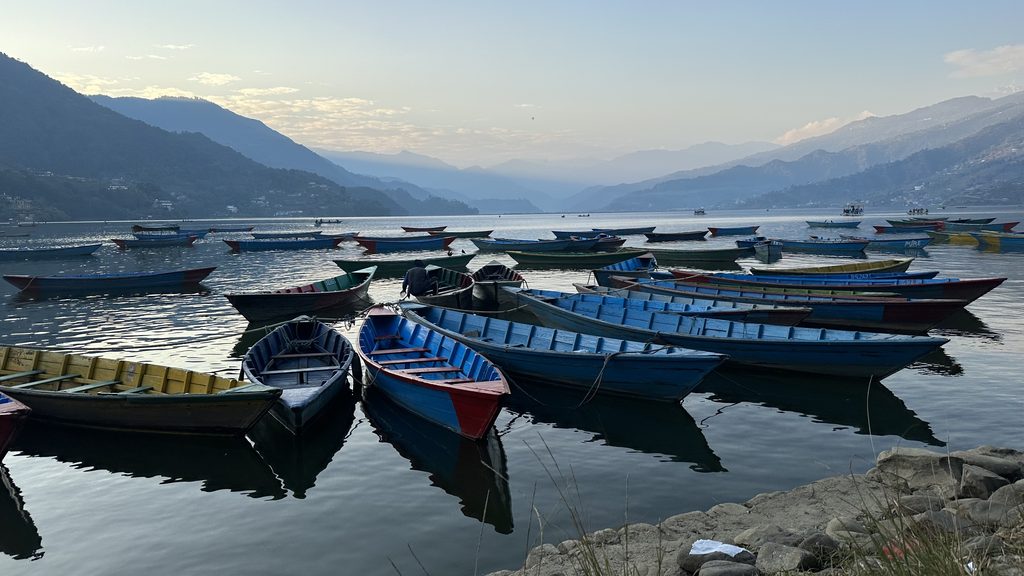 Barche tradizionali sull acqua del lago Phewa a Pokhara al tramonto